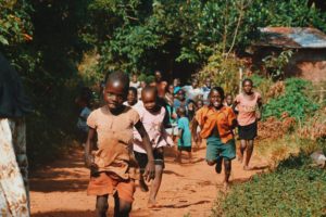 CEHZA children running and walking on brown sand surrounded with trees during daytime